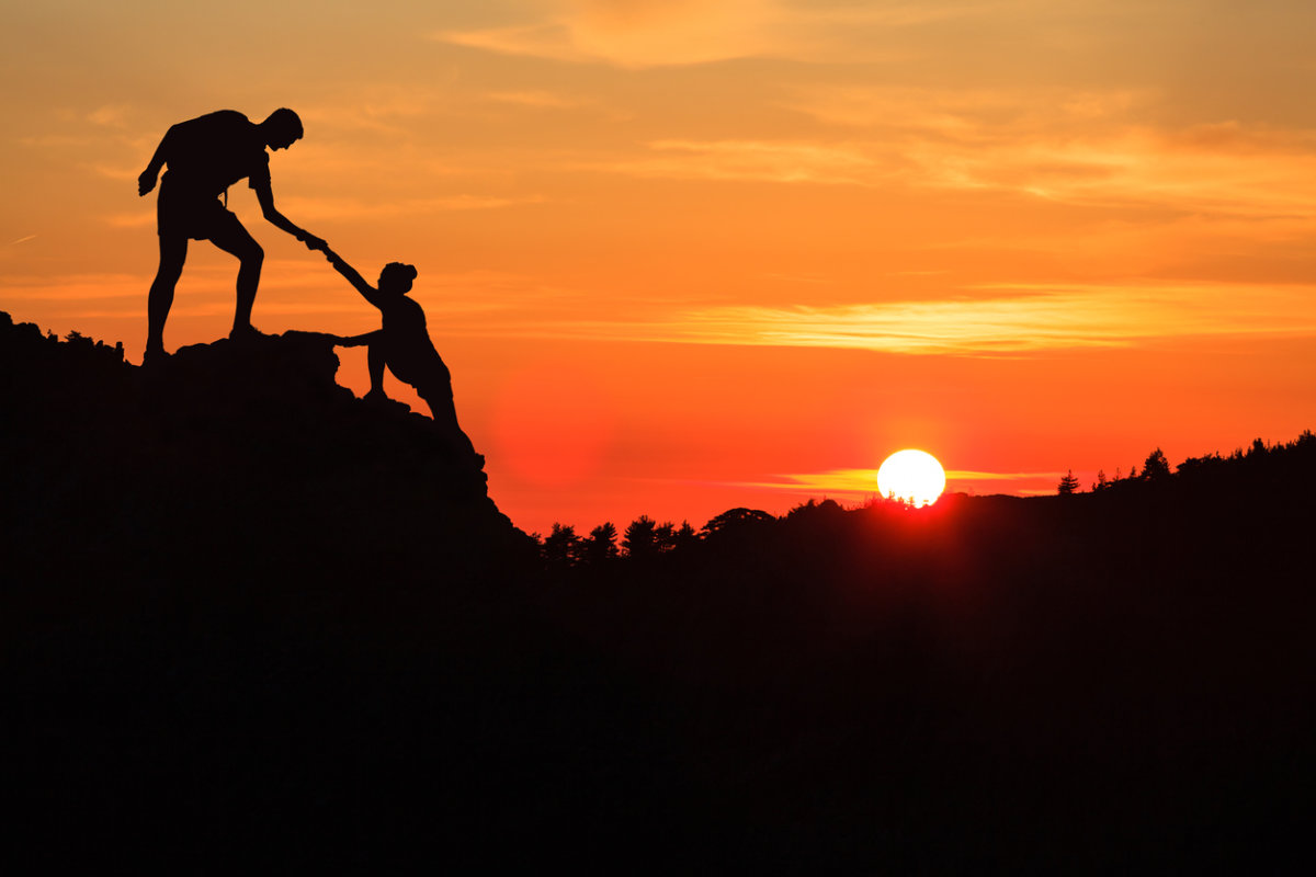 A couple of people standing on top of a hill.