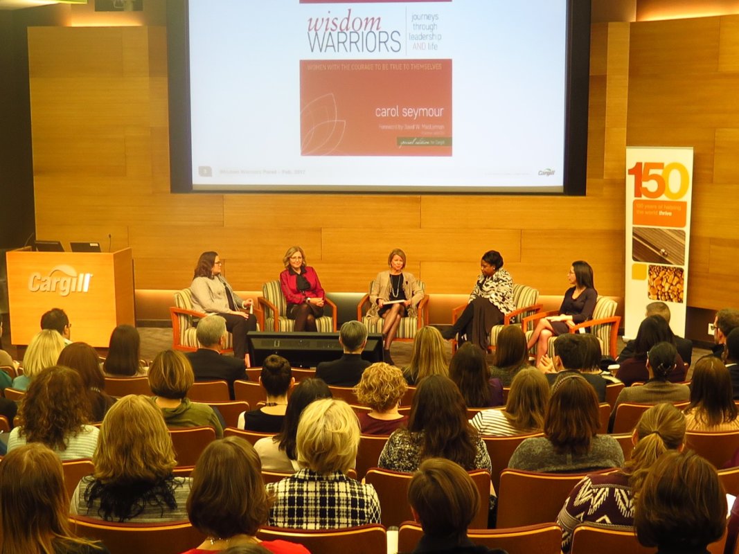 A group of women sitting in front of a crowd of people at the Signature Leaders seminar